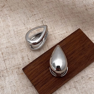 Macro shot of silver teardrop earrings with hollow and solid polished mirror finish