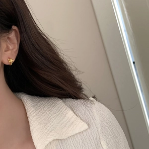 Close-up of elegant gold bow stud earrings worn by a model for a refined minimalist look