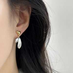 French style asymmetrical heart wing earrings with gold and silver metal textures on model