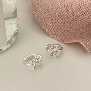 Macro view of silver bow-shaped hoop earrings with a polished metal finish