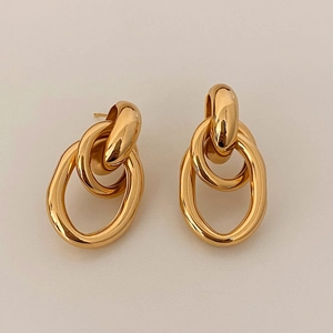 Détail de boucles d'oreilles créoles dorées ovales entrelacées au fini poli miroir