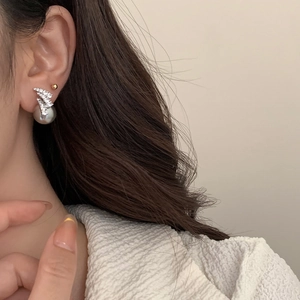 Detailed close-up of a lightning-shaped diamond stud earring with a large grey pearl on model