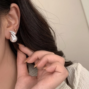 Close-up of elegant pearl earrings with sparkling zircon accents on model ear