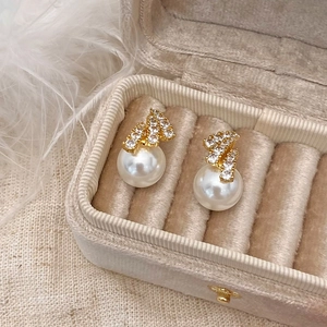 Close-up of geometric gold earrings with sparkling crystals and elegant white pearls