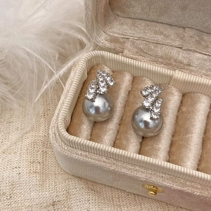 Close-up of elegant grey pearl earrings with sparkling zircon accents in a luxury gift box