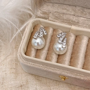 Detailed view of elegant pearl stud earrings with zircon accents in a velvet gift box