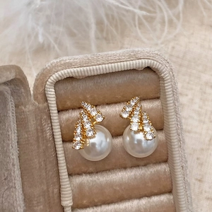 Macro view of elegant pearl stud earrings with sparkling zircons on a gold metal base