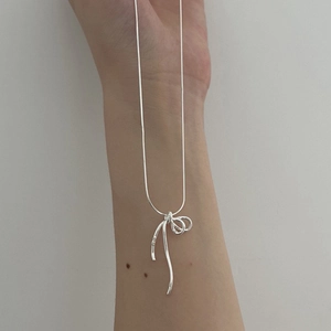 Détail du pendentif nœud en argent sur un collier élégant à chaîne serpent pour femme