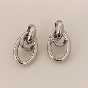 Vue détaillée des boucles d'oreilles ovales géométriques en argent poli sur fond beige