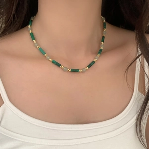 Collier artisanal perlé avec tubes de malachite verte et touches dorées sur mannequin