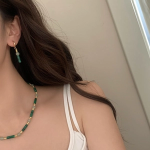 Gros plan d'un ensemble collier et boucles d'oreilles en malachite porté par un mannequin