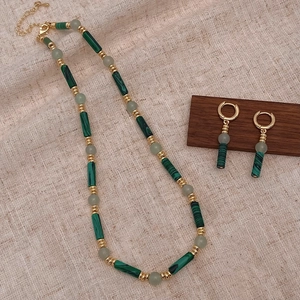 Détail du collier de perles style malachite verte et boucles d'oreilles sur lin