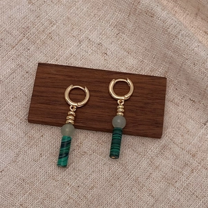 Détail de boucles d'oreilles rétro dorées avec perles en pierre naturelle verte