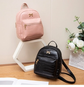 Detail of pink and black mini backpacks with crocodile texture and gold bow buckle