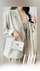 Elegante bolso acolchado blanco con cierre dorado lucido por una modelo en traje gris
