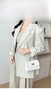 Detalle de bolso bandolera blanco acolchado con cierre dorado y asa superior elegante