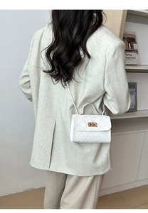 Bolso pequeño blanco acolchado con cierre giratorio dorado en escena de moda