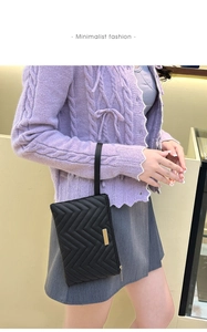 Detail of black quilted wristlet wallet featuring gold-tone zipper and metal logo plate