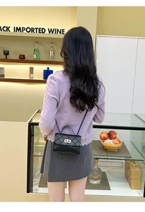 Vista trasera de una modelo llevando un mini bolso negro acolchado con cierre metálico