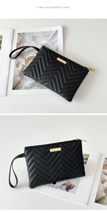 Detailed view of black V-quilted long wallet with gold metal plate and wrist strap