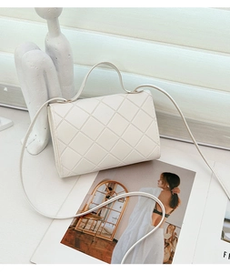 Primer plano de un bolso bandolera acolchado blanco con solapa y textura suave