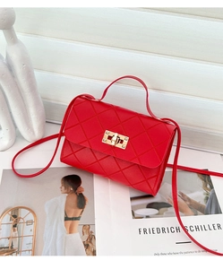 Detalle del bolso acolchado rojo con cierre giratorio dorado y textura de cuero fino