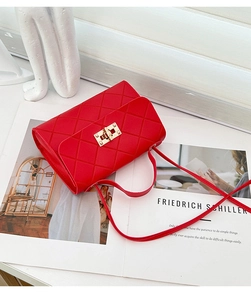 Detalle de bolso bandolera rojo acolchado con elegante cierre giratorio de metal dorado