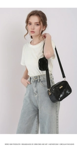 Detail of glossy black crossbody bag with wide strap and round mini coin pouch attachment