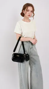 Detail of glossy black PU leather camera bag with wide strap and mini round coin purse