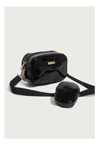 Macro detail of glossy black PU leather crossbody bag with gold metal plate and mini pouch