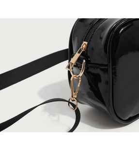 Detail of glossy black PU leather bag with golden metal zipper and nylon shoulder strap