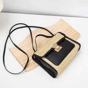Close-up of woven straw texture and black leather paneling on small crossbody bag