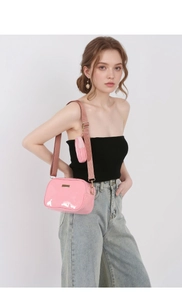 Close-up of pink patent leather crossbody camera bag with wide strap and mini coin pouch