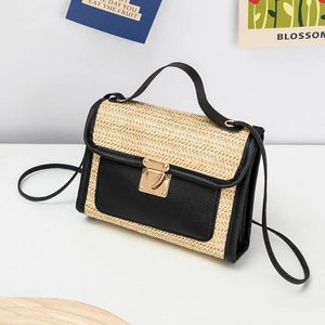 Detail view of woven straw crossbody bag featuring a golden heart swivel lock closure