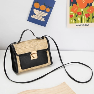 Detail of woven straw and black leather crossbody bag with golden heart clasp