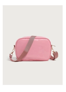 Close-up of pink patent leather crossbody bag with rose gold buckle and fabric strap