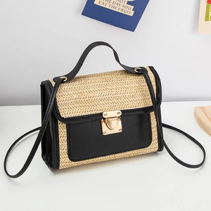 Detail of woven straw handbag featuring black leather trim and gold metal buckle clasp
