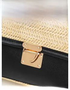 Close-up of woven straw texture with black faux leather trim and gold metal buckle