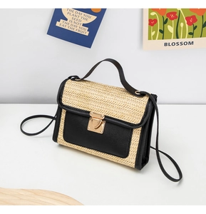 Detailed view of woven straw bag texture with heart-shaped golden metal clasp and leather flap