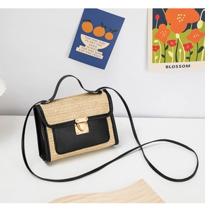 Detail of woven straw handbag with black leather trim and golden heart-shaped lock