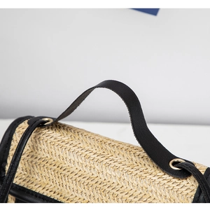 Detailed close-up of woven herringbone texture and black leather handle on the square bag