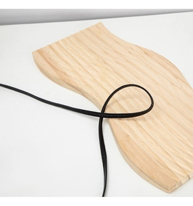 Macro shot of textured black cord on light wood background for fashion accessories