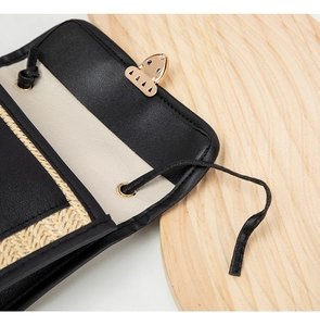 Detailed close-up of woven texture handbag featuring gold clasp and black leather trim