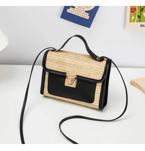 Detail of woven straw crossbody bag featuring heart-shaped gold clasp and leather trim