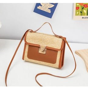 Detail of woven straw crossbody bag with brown leather trim and golden metal clasp lock