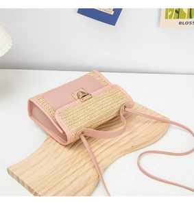 Detail of woven straw handbag with pink leather trim and golden metal square buckle