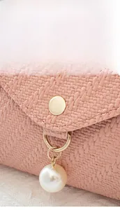 Close-up of pink woven texture featuring a gold metal clasp and a white pearl pendant