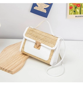 Close-up of woven straw handbag with white leather trim and gold square metal buckle