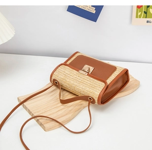 Close-up of retro woven straw crossbody bag with brown faux leather trim and gold lock