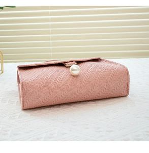Detail of pink crossbody bag with embossed texture and a large pearl charm on the flap